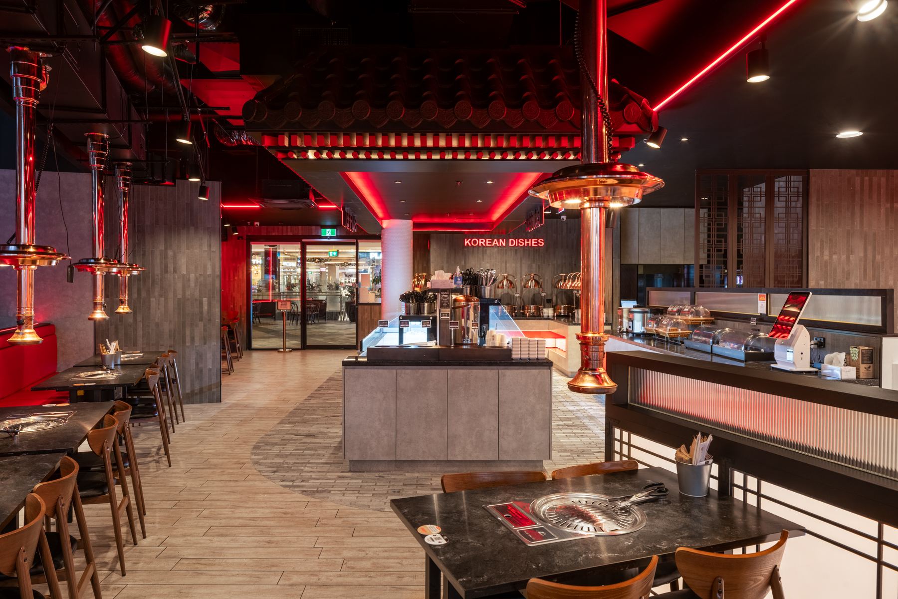 Dining floor beneath a suspended tiled-roof feature with red LED lighting