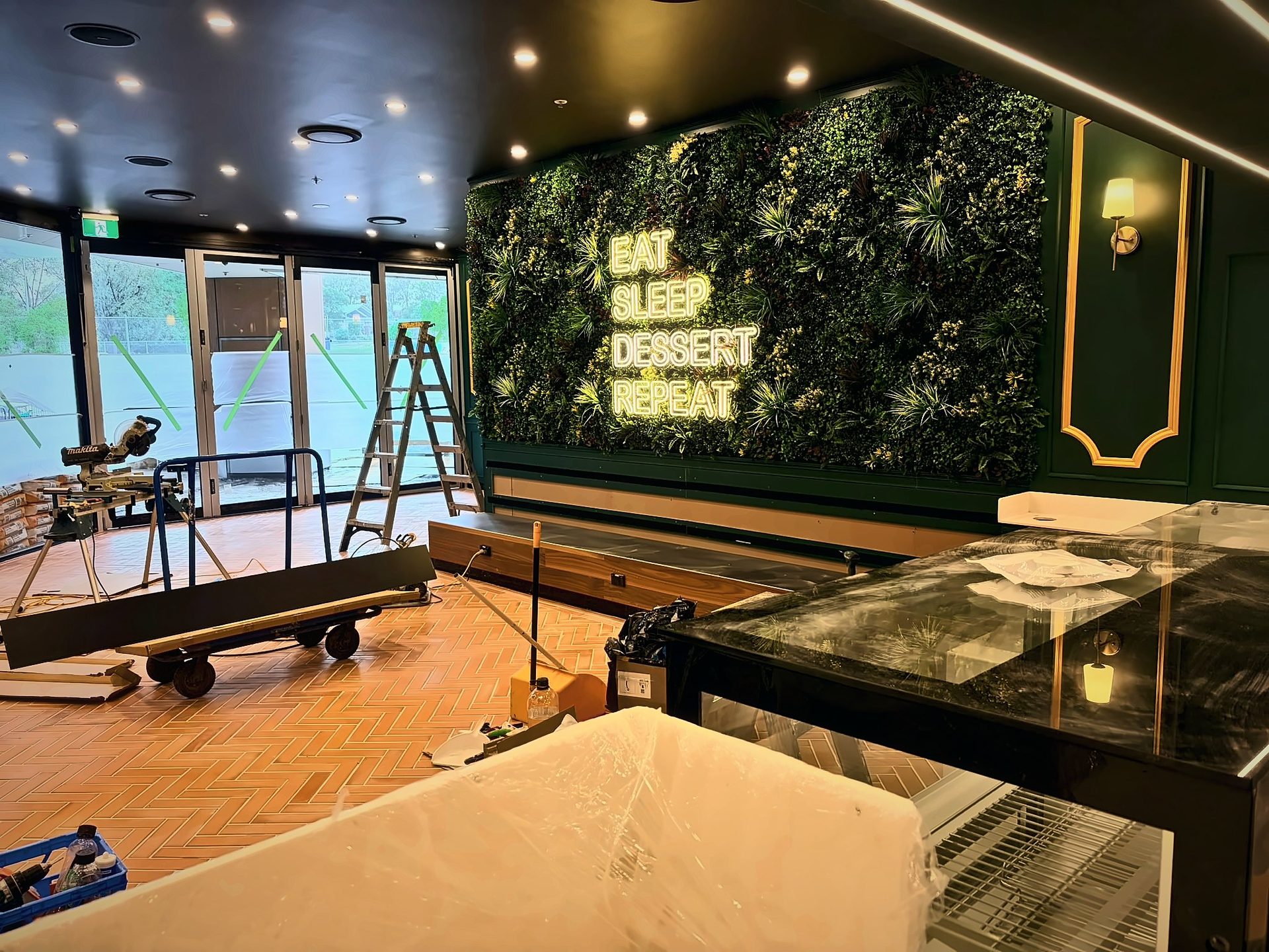 Oliver Brown shopfront glazing taped and protected, with the lit feature wall beyond